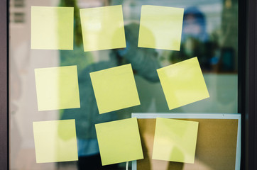 blank yellow sticky note or post note stuck on glass wall.