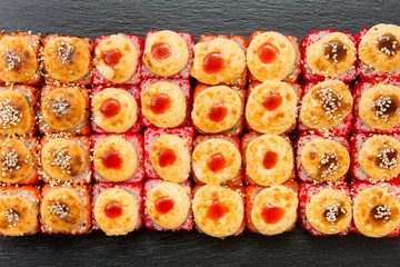 Japanese food set. Set of fried sushi rolls with fish and rice on black stone slate