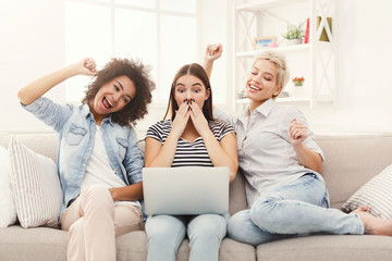 Naklejka na ściany i meble Three surprised women using laptop at home