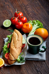 Lunch sandwich with cheese and vegetables served with citrus and coffee, selective focus, close-up, top view