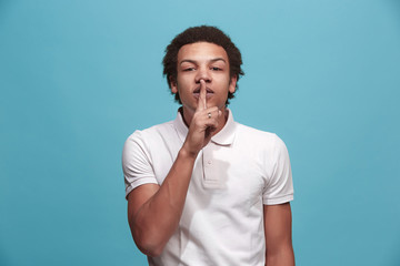 The young man whispering a secret behind her hand over blue background