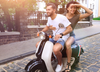 Plakat Young couple riding motor scooter in city