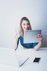 Young businesswoman using laptop, tablet and smart phone in her office. Blueish matte color filter, no retouch.