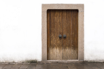 Traditional classic chinese wood door or gate with locked key and bronze lion head knob and white stone wall in ancient chinese house, china