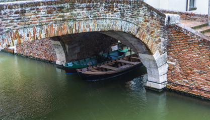 Boats under the bridge in Comacchio, Italy