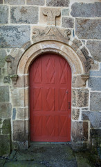 Fototapeta na wymiar Old red doors and scultpure above.
