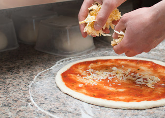 Cook in the kitchen putting the ingredients on the pizza. Pizza concept. Production and delivery of food.