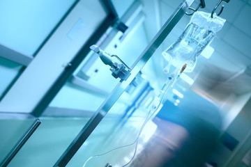 Silhouette of the doctor, blurred in motion, against the background of a dropper in the hospital corridor.
