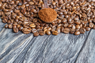 A coffee cup with coffee beans on an old wooden table. Fried coffee beans on a wooden background. Viewing from above.