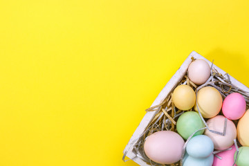 Multicolor eggs in a white tray. Creative Easter concept. Modern solid yellow background.