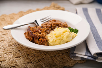 Pulled pork, beans and potato salad in a white bowl