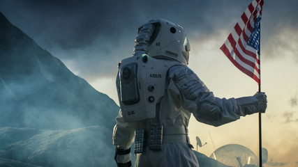 Strong Astronaut Walks with the Flag of Unites States of America on the Dark Alien Planet. Space Travel, Colonisation Theme.