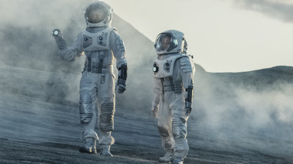 Fototapeta premium Two Astronauts Explore Rocky Alien Planet in the Day Time. Near Future and Technological Advance Brings Space Exploration, Travel, Colonization Concept.