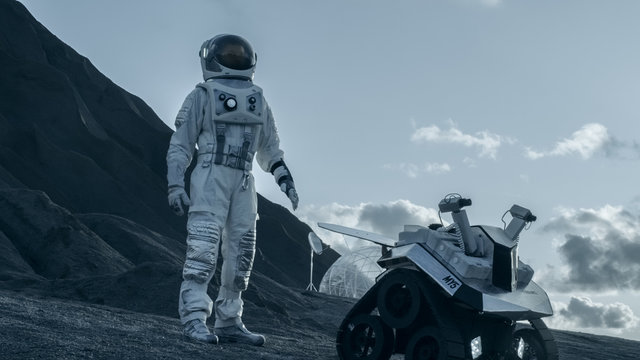 Astronaut Goes on the Expedition to Explore Rocky Alien Planet. In the Background His Base and AI Powered Rover. Futuristic Colonization Concept.