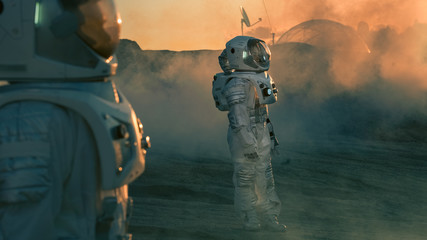Two Astronauts wearing Space Suits Standing on Alien Planet and Looking at Something. Futuristic...