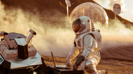 Astronaut in the Space Suit Works on Laptop, Adjusting Rover For Mars further Mars...