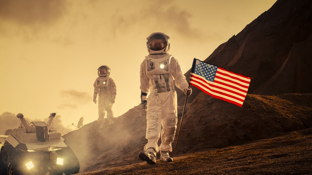 Two Astronauts Explore Mars/ Red Planet. One Cosmonaut Carries American Flag. Technological Advance Brings Space Exploration, Travel, Colonization Concept.