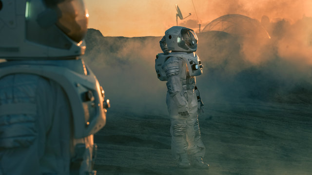 Two Astronauts wearing Space Suits Standing on Alien Planet and Looking at Something. Futuristic Space Exploration, Discovery and Colonization.