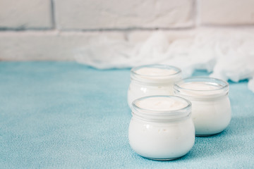 Homemade coconut milk yogurt in glass jars on light blue background. Selective focus, copy space.