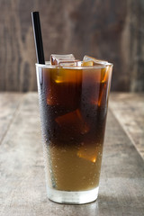 Iced coffee in glass on wooden table. Copyspace