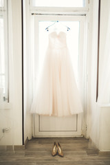 Fashion wedding dress for bride hanging near window