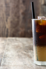 Iced coffee in glass on wooden table. Copyspace