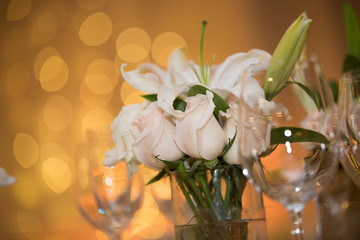 Beautiful white flowers with bokeh warm night lights background. Closeup of centerpieces at a wedding reception. White roses.