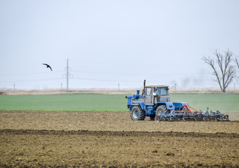 Lush and loosen the soil on the field before sowing. The tractor plows a field with a plow