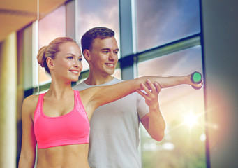 smiling young woman with personal trainer in gym