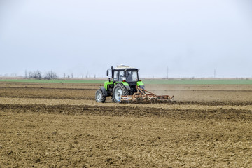 Lush and loosen the soil on the field before sowing. The tractor plows a field with a plow