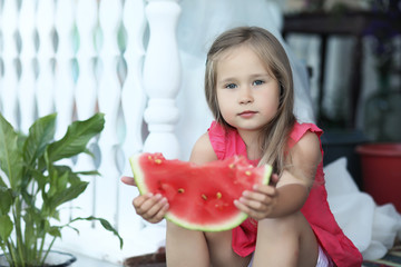 Young girl on the porch of the house eating sweet watermelon