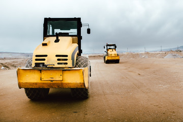 Two Vibratory Soil Compactors on construction site. Industrial roadworks at highway with heavy-duty machinery