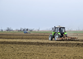Fototapeta na wymiar Lush and loosen the soil on the field before sowing. The tractor plows a field with a plow
