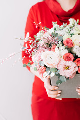 Florist woman holding a beautiful fresh blossoming flowers bouquet on the grey wall background
