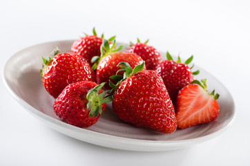Fresh ripe red strawberries in white plate on white background