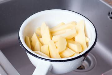 Draining boiled potato slices in colander