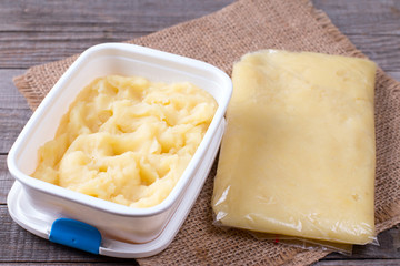 Mashed potatoes in a container and a bag on a table