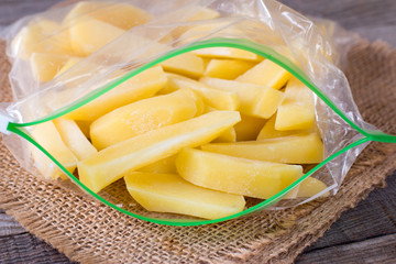 Frozen potatoes in a bag on a wooden table. Frozen food