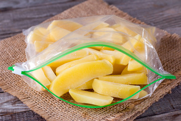 Frozen potatoes in a bag on a wooden table. Frozen food