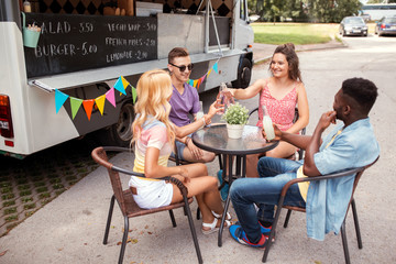 friends clinking bottles with drinks at food truck