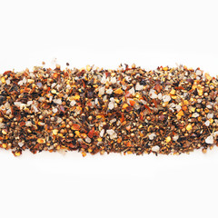 Strip of heap of hot meat seasoning, isolated on white background. Top view. Mix of spices. Black pepper corns, paprika, coriander, garlic, sea salt, satureja, basil, chili. Seasoning for meat dishes