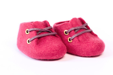 Pink handmade baby shoes made of merino wool on a white background.