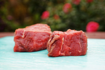 Two pieces of tenderloin beef on blue board, toned image
