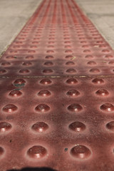 Blind pedestrian walking and detecting markings on tactile paving with textured ground surface indicators for blind and visually impaired.