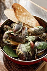 Mussels cooked with curry and served in metal pot, Asian food, toned