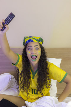 Brazilian girl supporter accompanying the game on TV screen, cell phone and laptop - Celebrating a goal - Nervous