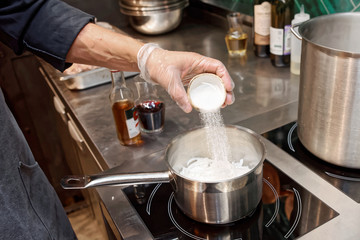 Fototapeta na wymiar Chef is adding sugar to the pan, toned