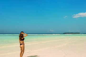 Fototapeta na wymiar Woman spending summer holiday sunbathing on the Zanzibar beach during sunny day