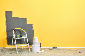 Set with decorator tools and paint on floor near color wall