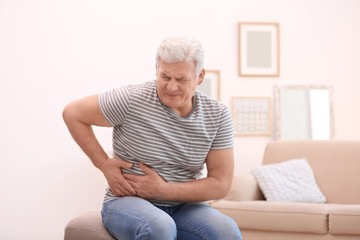 Mature man suffering from pain in his side at home